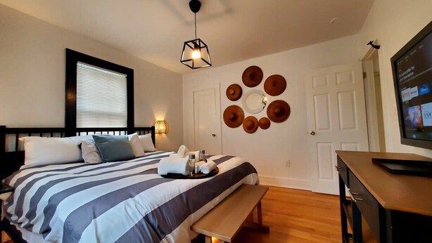 A neatly arranged bedroom with a bed, bedside table, bench, and wall decor. - The Blue Sapphire: Modern & Stylish 2BR w/ 2 King Beds & Full Kitchen (Bridgeport)