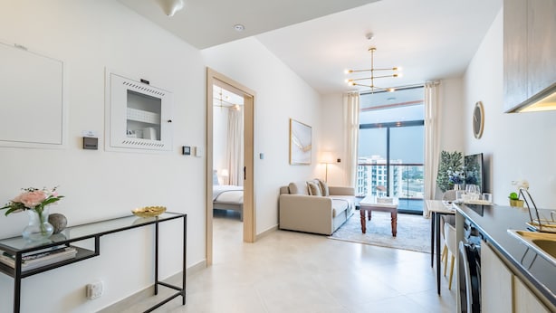 Eine moderne Wohnung mit einem Glastischchen, einer Couch, einem Essbereich und Blick auf die Stadt.