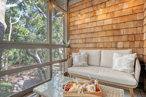 Una pared de madera, un sofá de mimbre y una mesa con comida y bebidas.