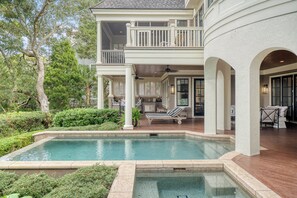 A two-story house with a pool, outdoor seating, and a covered patio area. - Enviable location, pool with breathtaking scenery at every turn. (Kiawah Island)