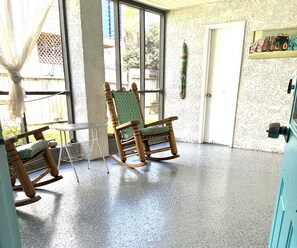 Une pièce avec un fauteuil à bascule, une petite table et une porte.