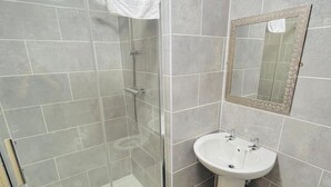 A bathroom with a glass shower enclosure, a white sink, and a toilet. - The Talbot Hotel (Stourbridge)