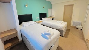 A hotel room with two beds, a small desk, a mirror, and a door. - The Talbot Hotel (Stourbridge)