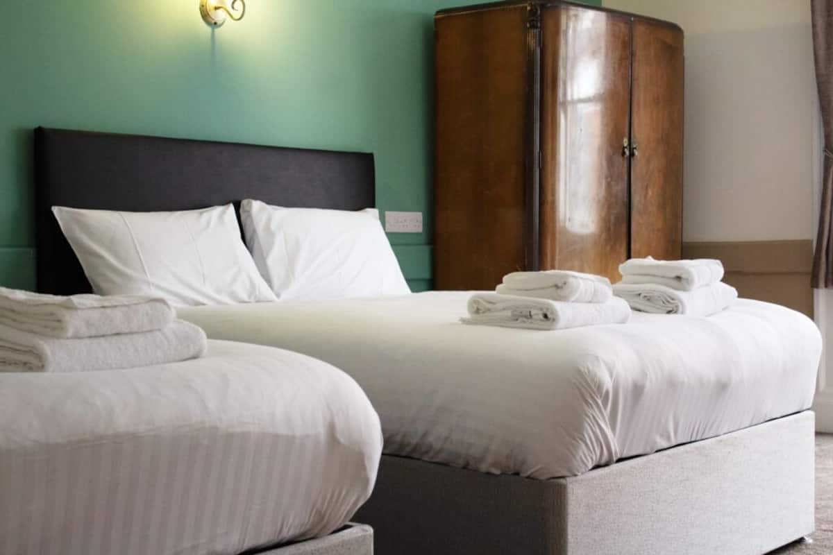 Habitación de hotel con dos camas, un armario y una lámpara fijada a la pared.