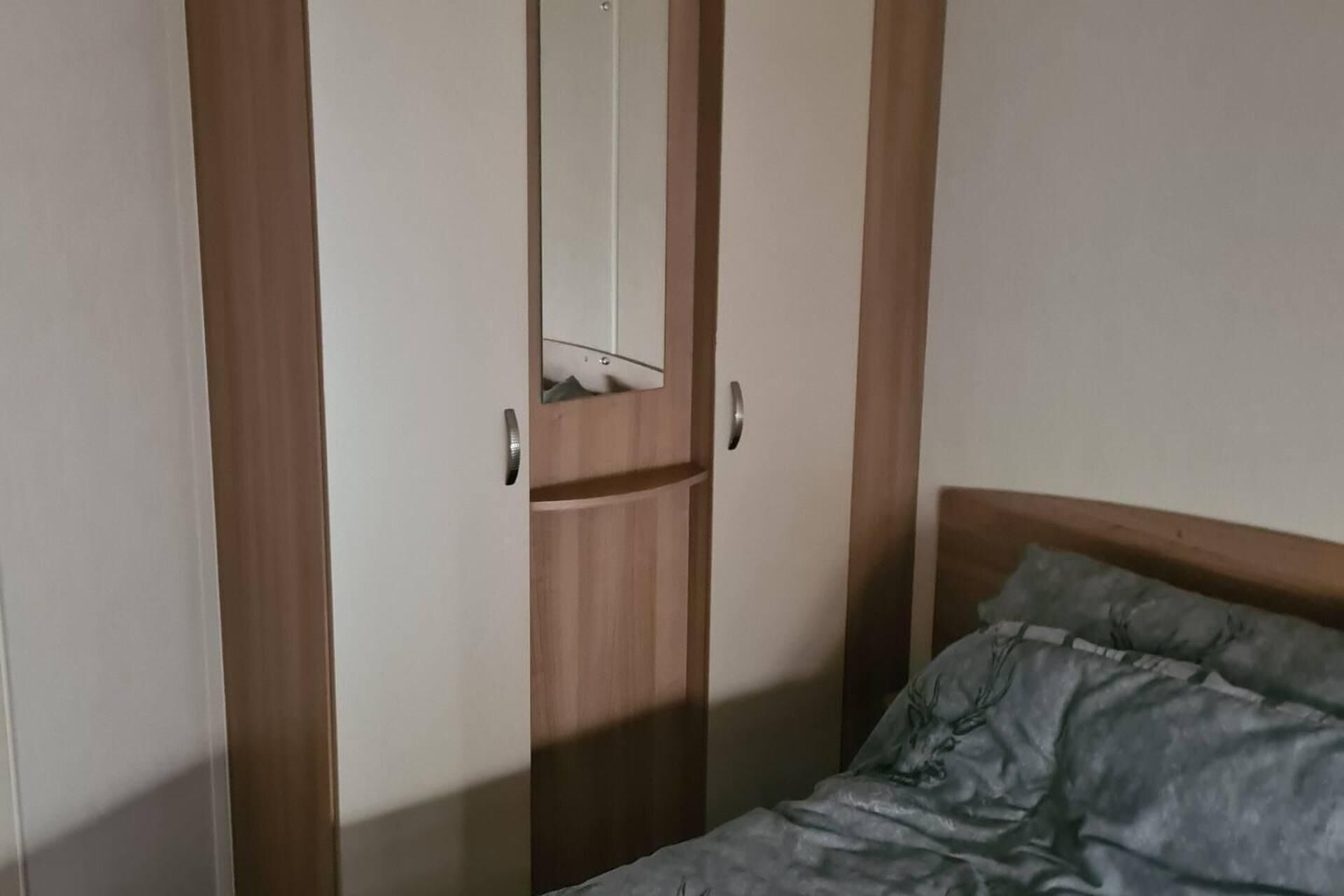Une chambre à coucher avec un lit, une armoire en bois et un miroir.