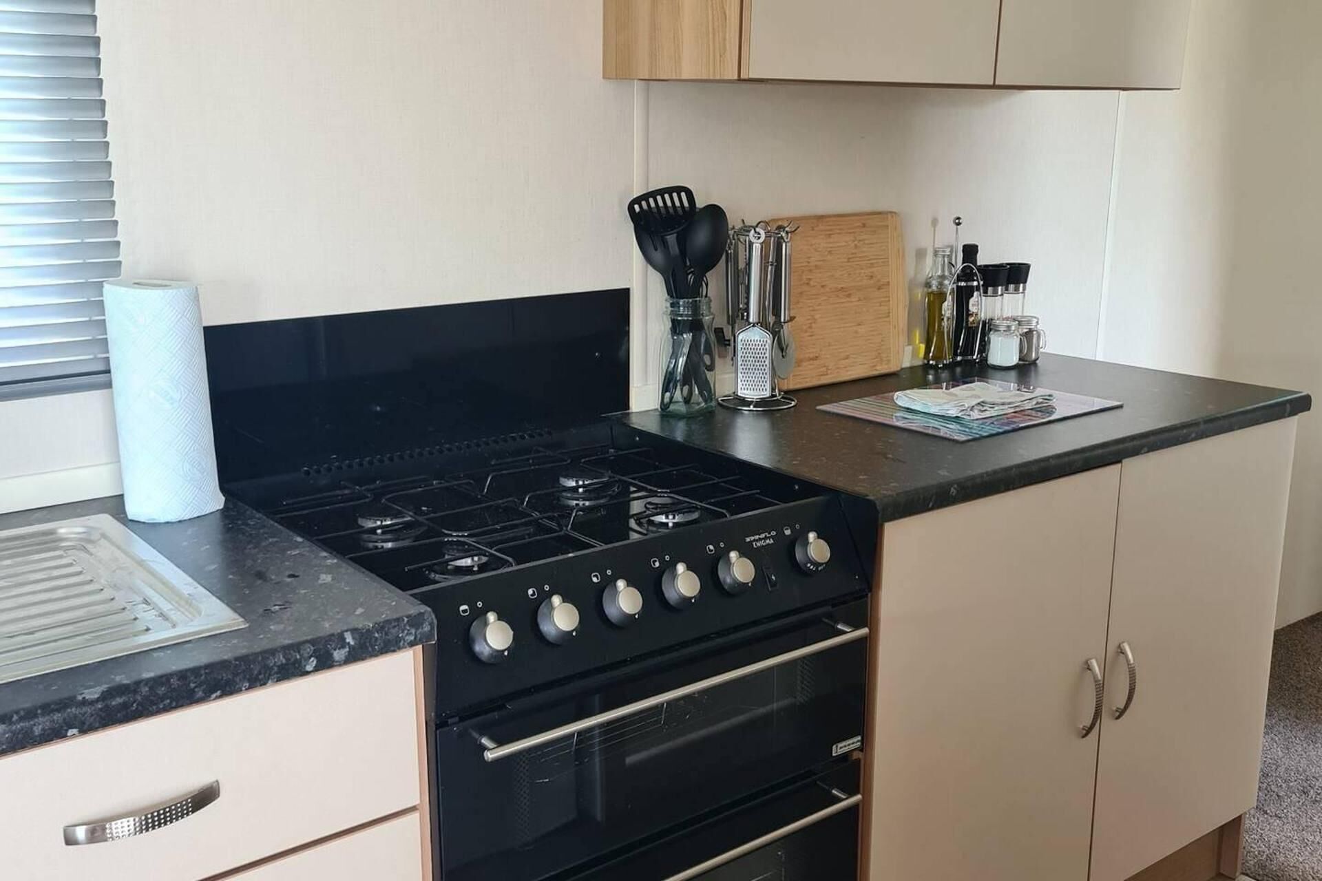 A kitchen with a black stove, a sink, and cabinets.