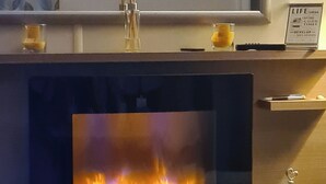 A fireplace with a glass front, bookshelves below, and decorative items on the mantel. - 2 Bed Lodge - Sleeps 6 - Parking - Pets - Wifi (Millom)