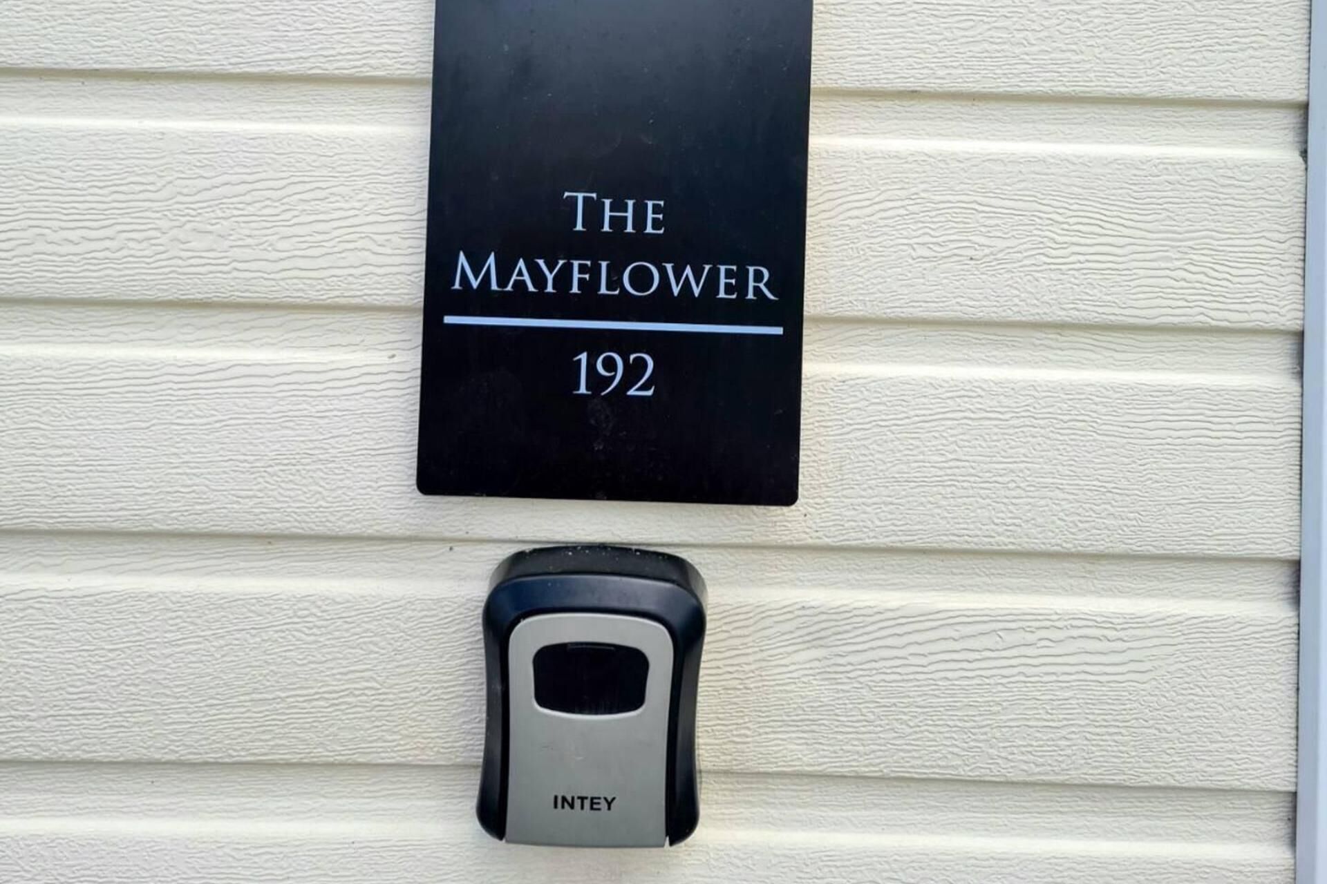 A black sign with "The Mayflower 192" on a textured white wall.