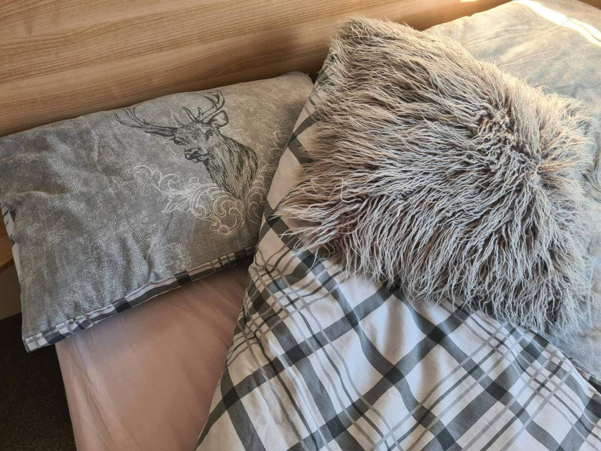 Un lit avec une couverture à carreaux et un oreiller orné d’un motif de cerf.