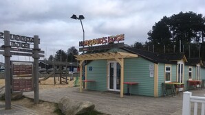 A beach cafe with a sign reading "HARDY'S EDGE BEACH CAFE & WATERSPORTS". - Lavender super front row sea view caravan at Rockley Park, Poole Harbour, Dorset (Poole)