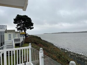 A coastal view with a white fence, a tree, and a body of water. - Lavender super front row sea view caravan at Rockley Park, Poole Harbour, Dorset (Poole)
