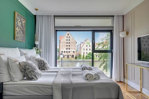 Habitación de hotel con una cama grande, televisión y vistas a edificios por la ventana.