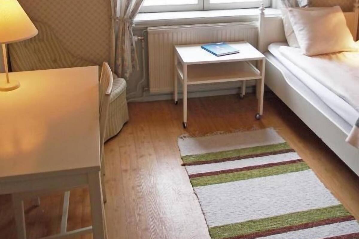 Une petite pièce, bien rangée, avec un lit, un bureau et un radiateur.