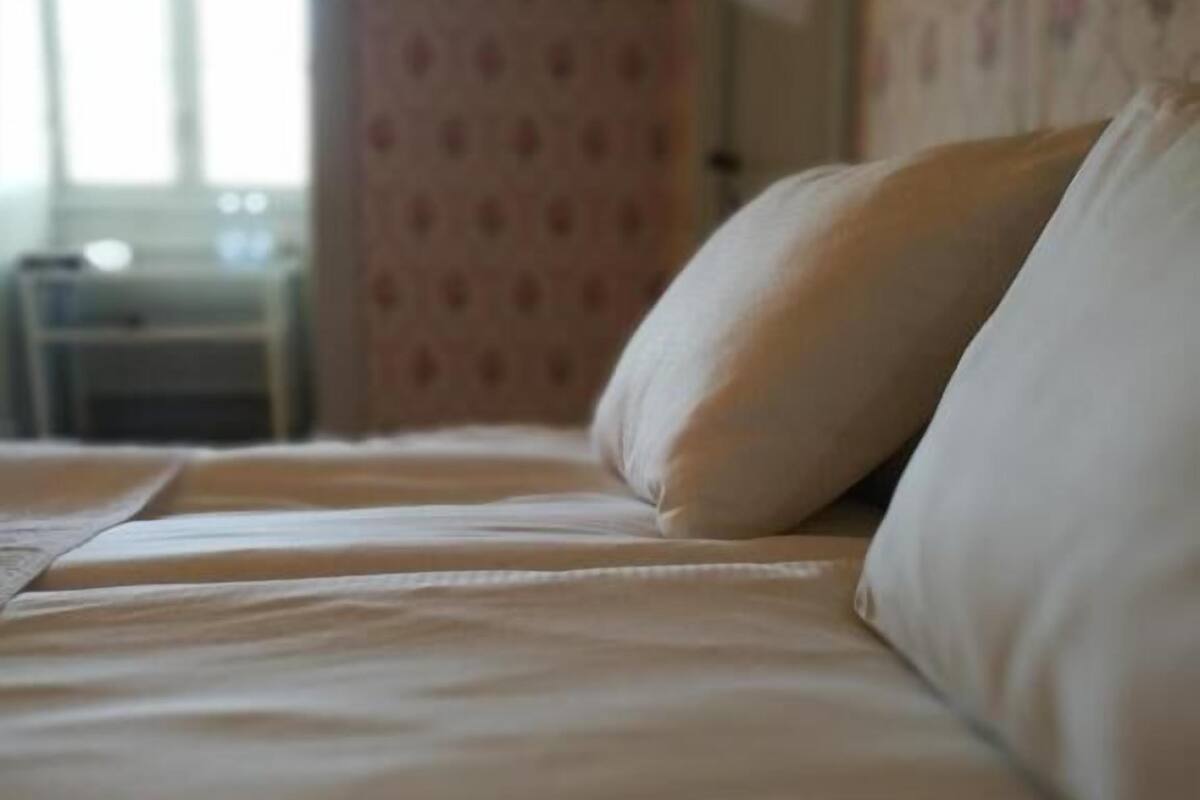 Un lit avec un oreiller blanc et une lampe sur une table de chevet.
