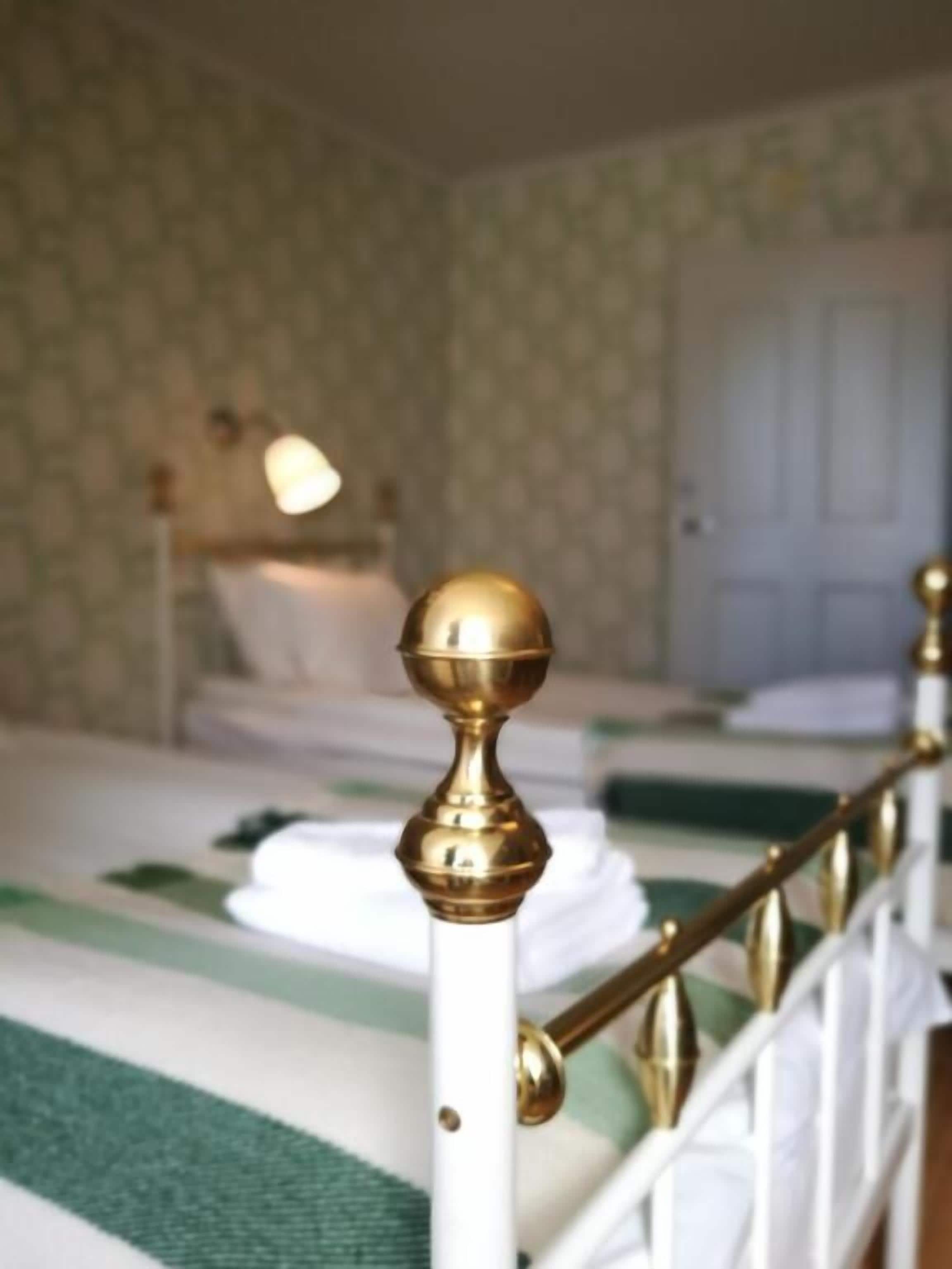 Habitación de hotel con una cama que tiene un cabecero blanco y un detalle decorativo dorado.