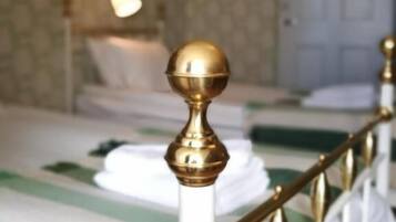 Habitación de hotel con una cama que tiene un cabecero blanco y un detalle decorativo dorado.