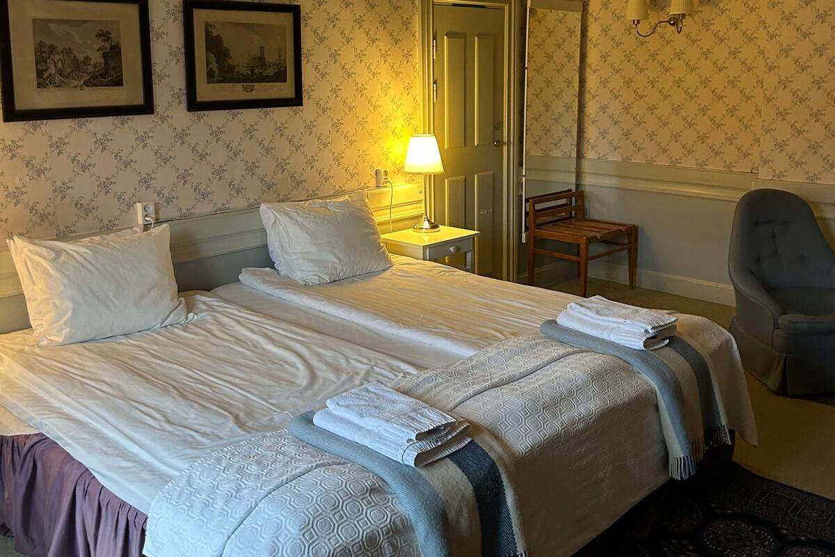 Une chambre d’hôtel avec un grand lit, deux tables de chevet, une chaise et un miroir.