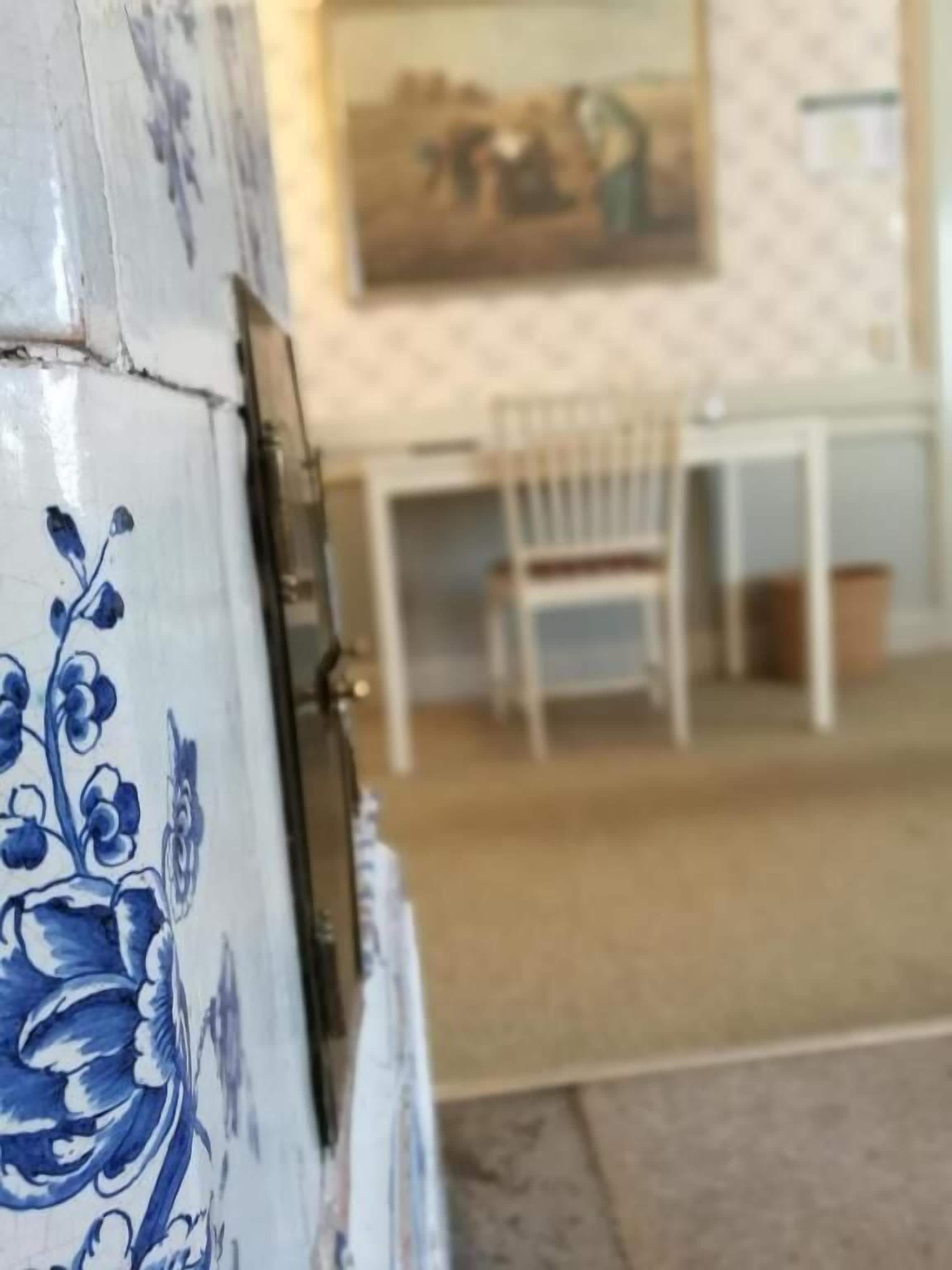 Una habitación con una pared blanca, un cuadro, una mesa blanca y una silla.