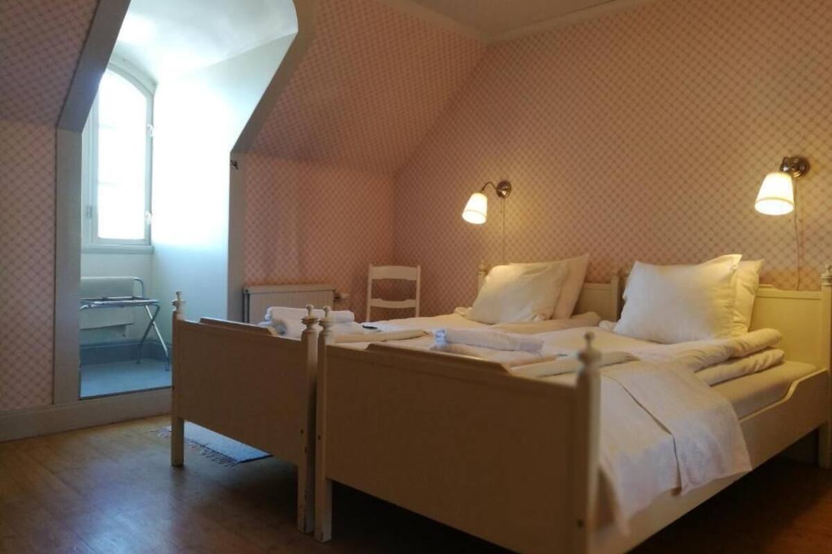 Une chambre à coucher avec un lit en bois, deux lampes de chevet, une fenêtre et une chaise.