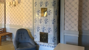 Een kamer met een blauwe wand met bloemendesign, een houten stoel, een witte tafel en een decoratief wandobject.