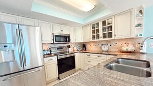 Una cocina moderna con armarios blancos, electrodomésticos de acero inoxidable, encimera de granito y horno integrado.