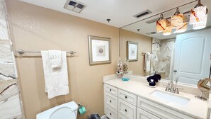 Un baño con inodoro, lavamanos, tocador y barra para toallas.
