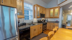 Una cocina moderna con armarios de madera, electrodomésticos de acero inoxidable y un comedor con mesa y sillas de madera.