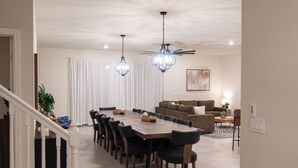 A spacious dining area with a long wooden table, black chairs, and two hanging pendant lights. - Luxury 10 Bed w/Pool, Home Theater, & Gameroom! (Davenport)