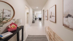 A hallway with a black console table, a mirror, and framed artwork on the walls. - Luxury 10 Bed w/Pool, Home Theater, & Gameroom! (Davenport)