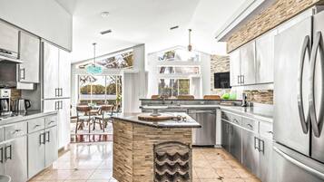 A modern kitchen with a central island, stainless steel appliances, and a view to the outdoors.