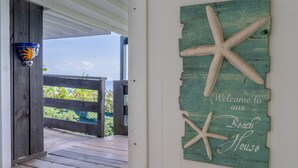 A wooden deck with a rustic sign reading "Welcome to our Beach House" and starfish decorations. - Studio apartment above Horseshoe Bay beach (Southampton Parish)