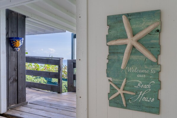 A wooden deck with a rustic sign reading "Welcome to our Beach House" and starfish decorations. - Studio apartment above Horseshoe Bay beach (Southampton Parish)