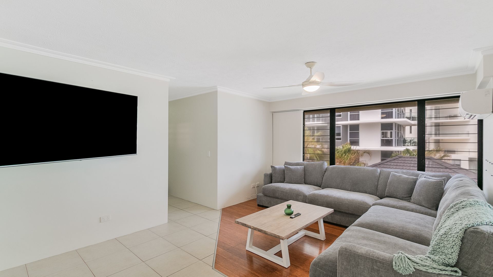 A modern living room with a grey sectional sofa, a wooden coffee table, and a ceiling fan.
