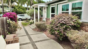 A residential house with a paved driveway, a wooden fence, and various plants. - New Remodel, Minutes to Beach, Perfect for 2 (Long Beach)