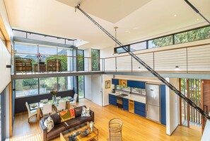 Un appartement en duplex spacieux, comprenant un coin repas, une cuisine et un escalier reliant les deux niveaux.