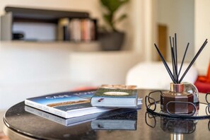 A table with books, a glass vase with reed sticks, and a pair of glasses.