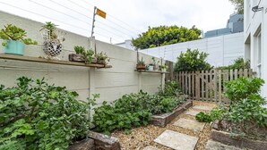 A garden with stone pathways, various potted plants, and a wooden fence. - 3 Bedroom Family Home - Houtbay (Cape Town)