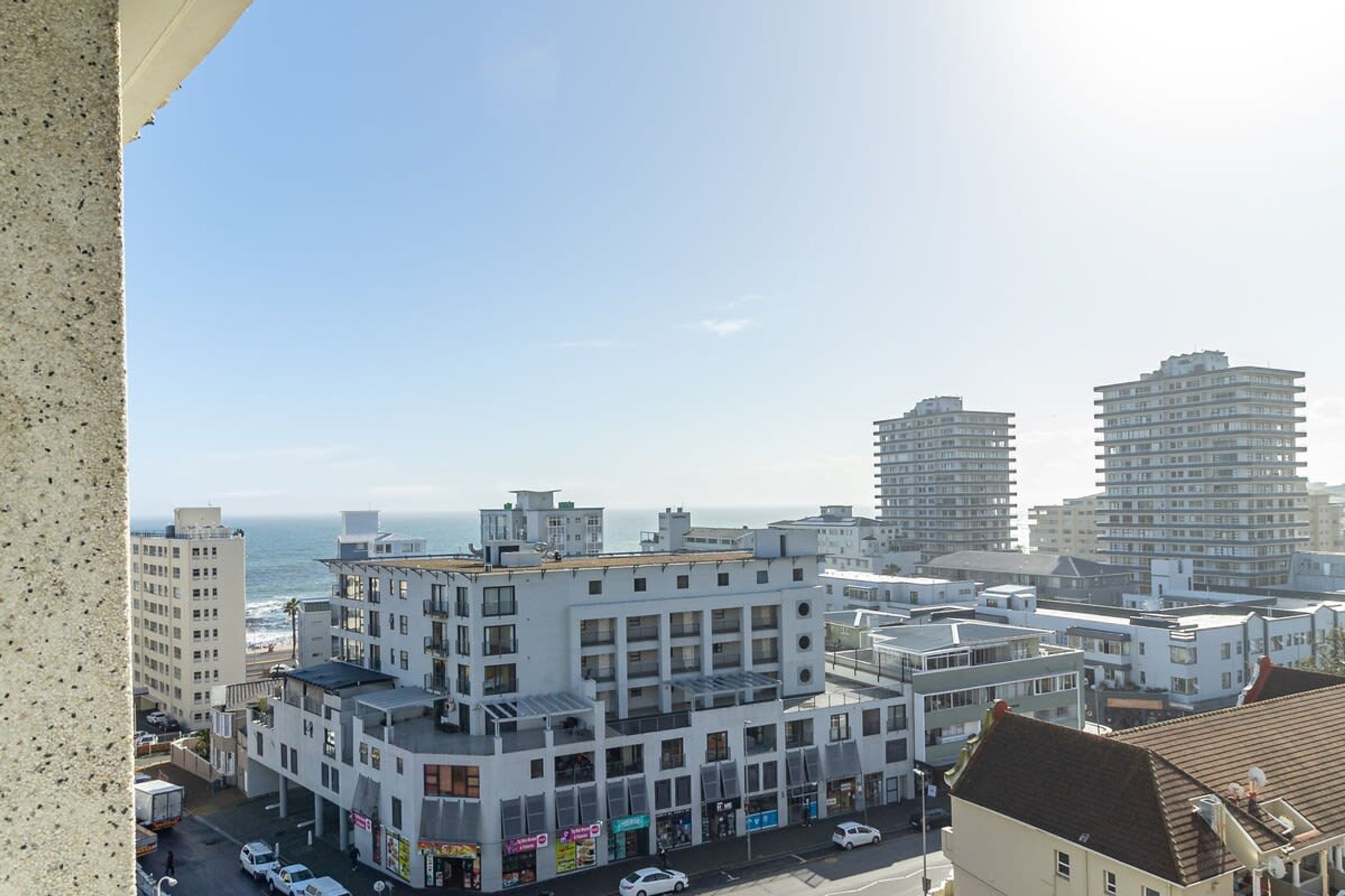 A modern building with multiple floors, a flat roof, and a view of the ocean.