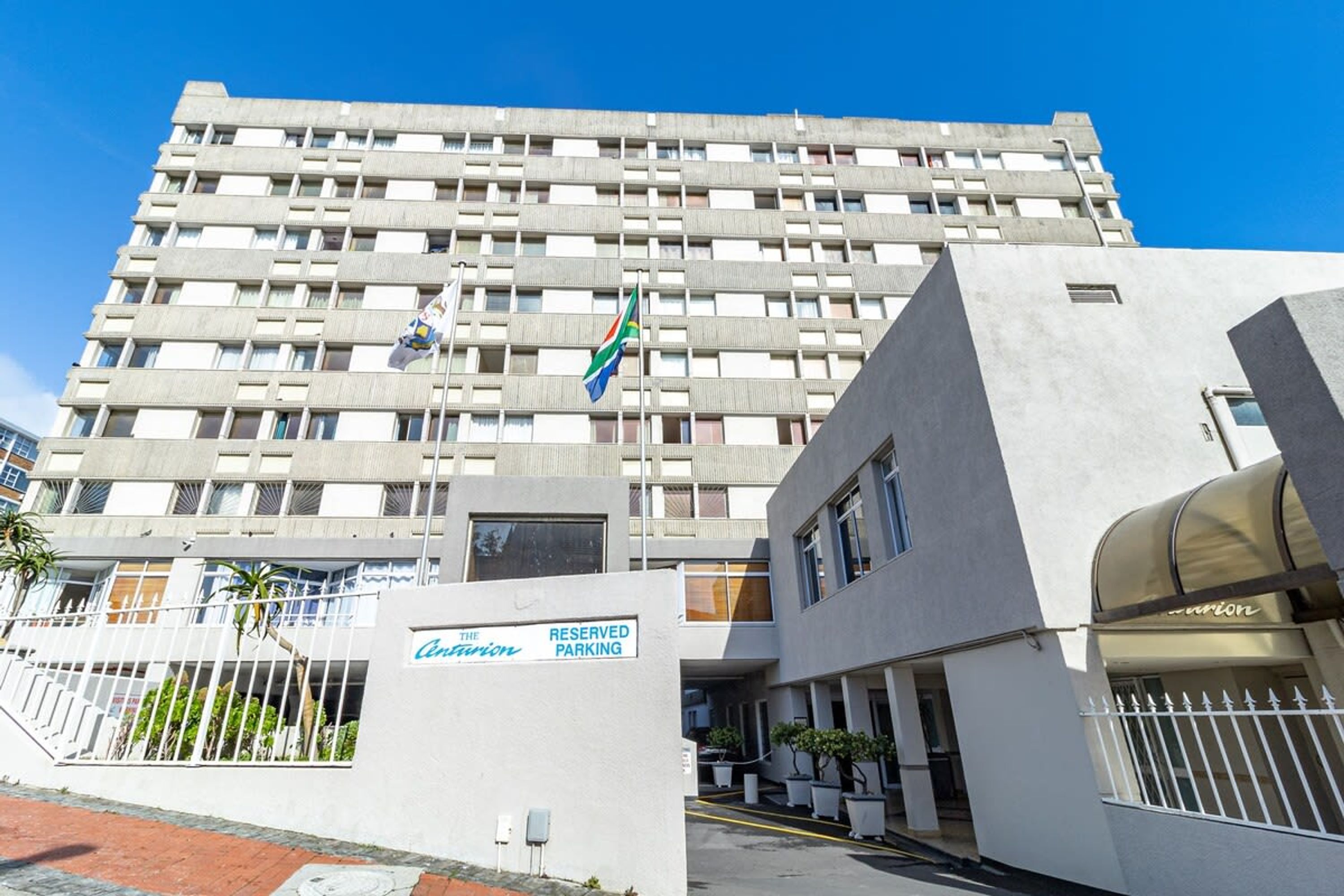 A multi-story hotel with a modern design, featuring a reserved parking area and a flag.