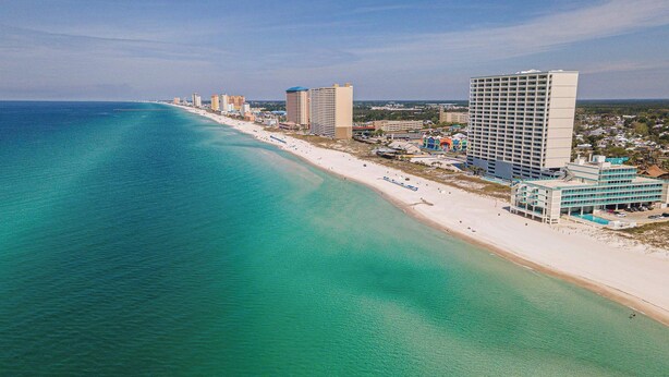 A coastal hotel with a beach view, multiple high-rise buildings, and a clear blue sea.