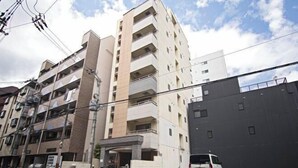 A multi-story residential building with balconies, a covered entrance, and a parked white van. - Daikoku Apartment 603 - Namba Apt3 minJR Imamiya/Daikokucho St/Veranda (Osaka)