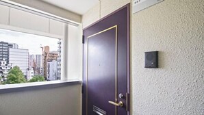 A door with a window above it, a textured wall, and a small electronic device mounted on the wall. - Daikoku Apartment 603 - Namba Apt3 minJR Imamiya/Daikokucho St/Veranda (Osaka)