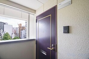 A door with a window above it, a wall-mounted intercom, and a view of buildings outside. - Daikoku Apartment 603 - Namba Apt3 minJR Imamiya/Daikokucho St/Veranda (Osaka)