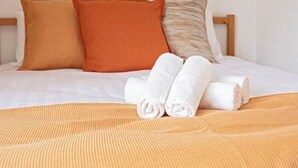 A neatly made bed with a striped bedspread, two rolled towels, and three pillows in varying shades. - Daikoku Apartment 603 - Namba Apt3 minJR Imamiya/Daikokucho St/Veranda (Osaka)