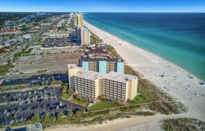 A coastal hotel with multiple floors, a parking lot, and a beachfront. - Seaside Villa | Ocean View, Pool | Activity Experiences (Panama City Beach)