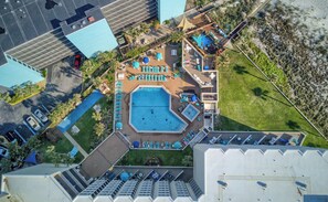 An aerial view of a hotel with a swimming pool, sun loungers, and a parking area. - Seaside Villa | Ocean View, Pool | Activity Experiences (Panama City Beach)