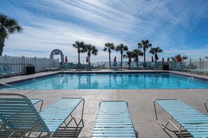 A swimming pool with lounge chairs and palm trees. - The Turtle Nest | Pool, Beach Access | Activity Experiences (Panama City Beach)