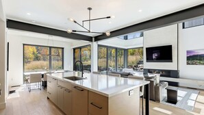 Een moderne keuken met een groot eiland, een zithoek met een bank en een open haard.