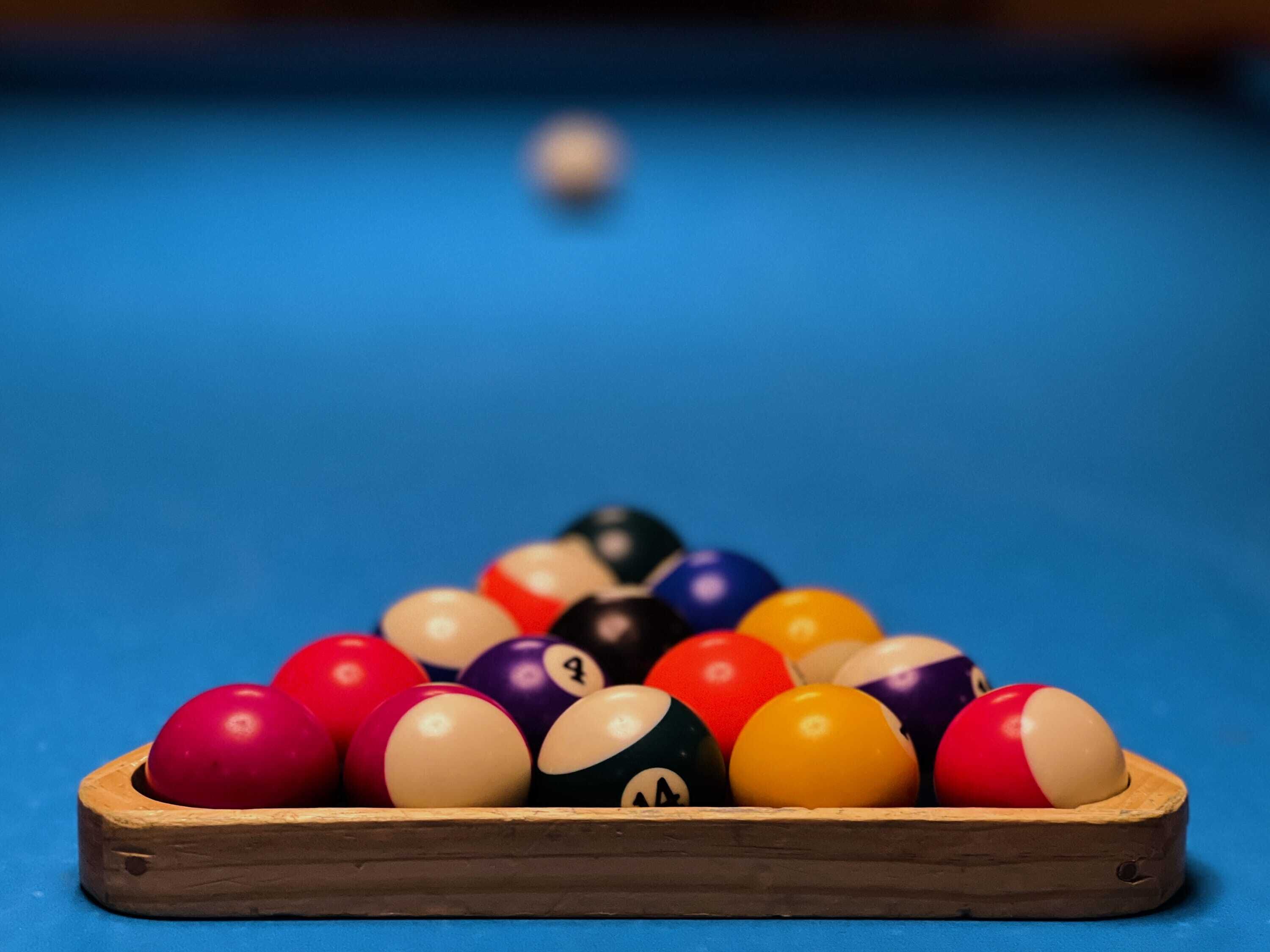 A pool table with a wooden edge and a blue felt surface.