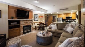 Una sala de estar moderna con chimenea, televisor de pantalla plana, comedor y cocina con armarios de madera.